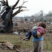 A woman carries a child through a field near the collapsed Plaza Towers Elementary School in Moore, Okla., Monday, May 20, 2013. The relationship between the woman and the child was not immediately known. A tornado as much as a mile (1.6 kilometers) wide with winds up to 200 mph (320 kph) roared through the Oklahoma City suburbs Monday, flattening entire neighborhoods, setting buildings on fire and landing a direct blow on an elementary school. 